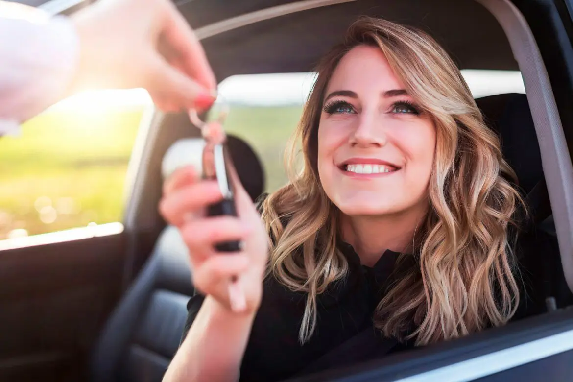 A woman sitting in the back of a car holding her phone.