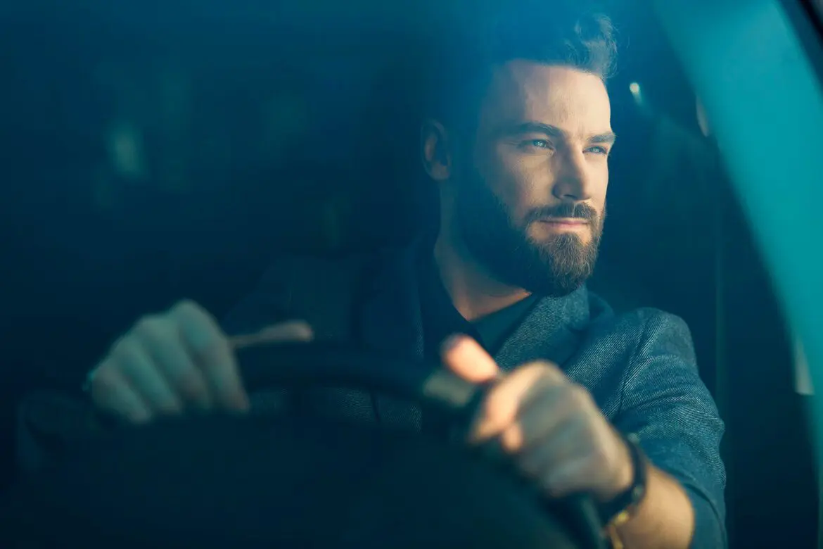 A man driving in the dark with his beard.