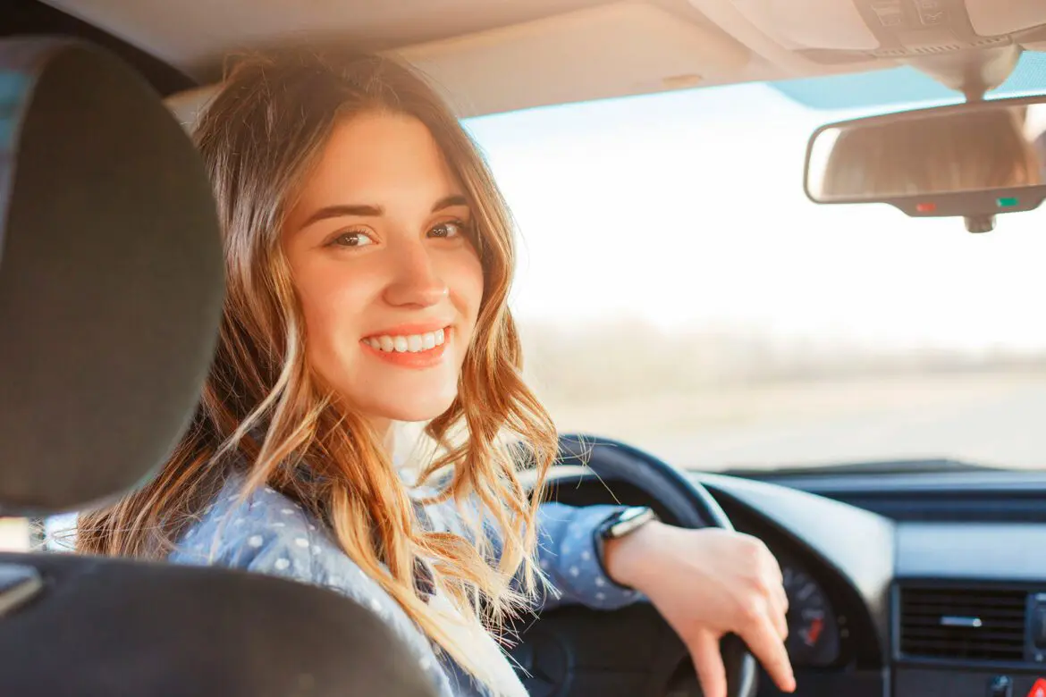 A woman sitting in the driver 's seat of her car.