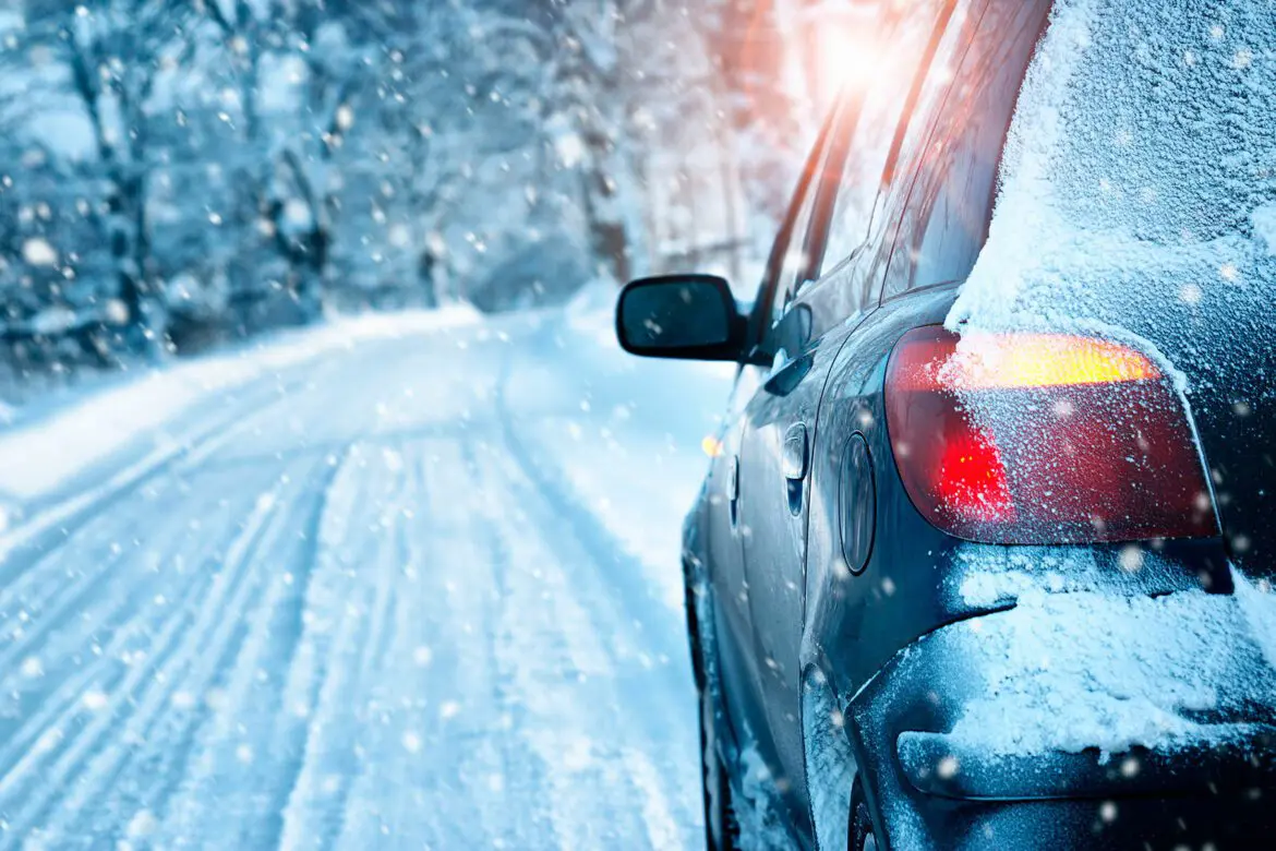 A car driving down the road in winter.