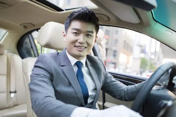 A man in a suit sitting inside of a car.