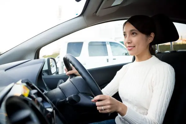 A woman sitting in the drivers seat of her car.