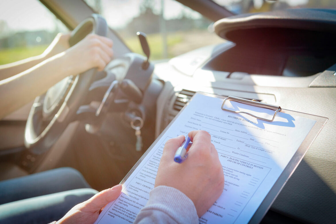 A person filling out paperwork in the drivers seat of a car.