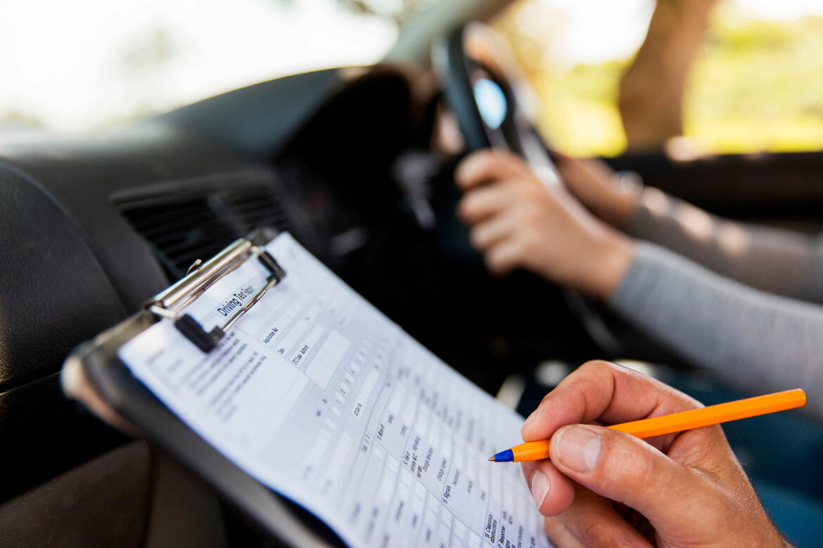 A person writing on paper in front of a car.
