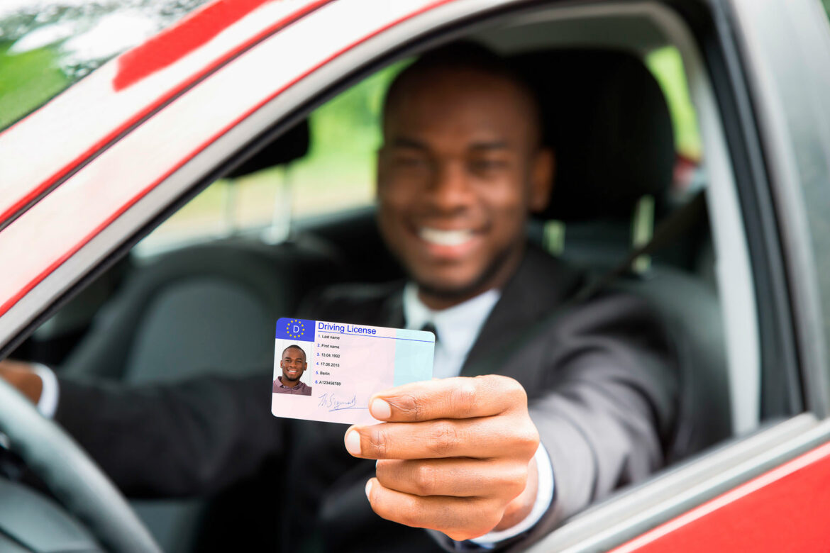 A man holding his driver 's license in the car.