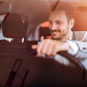 A man is driving in the car and smiling.