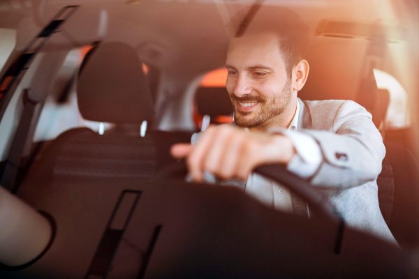 A man is driving in the car and smiling.