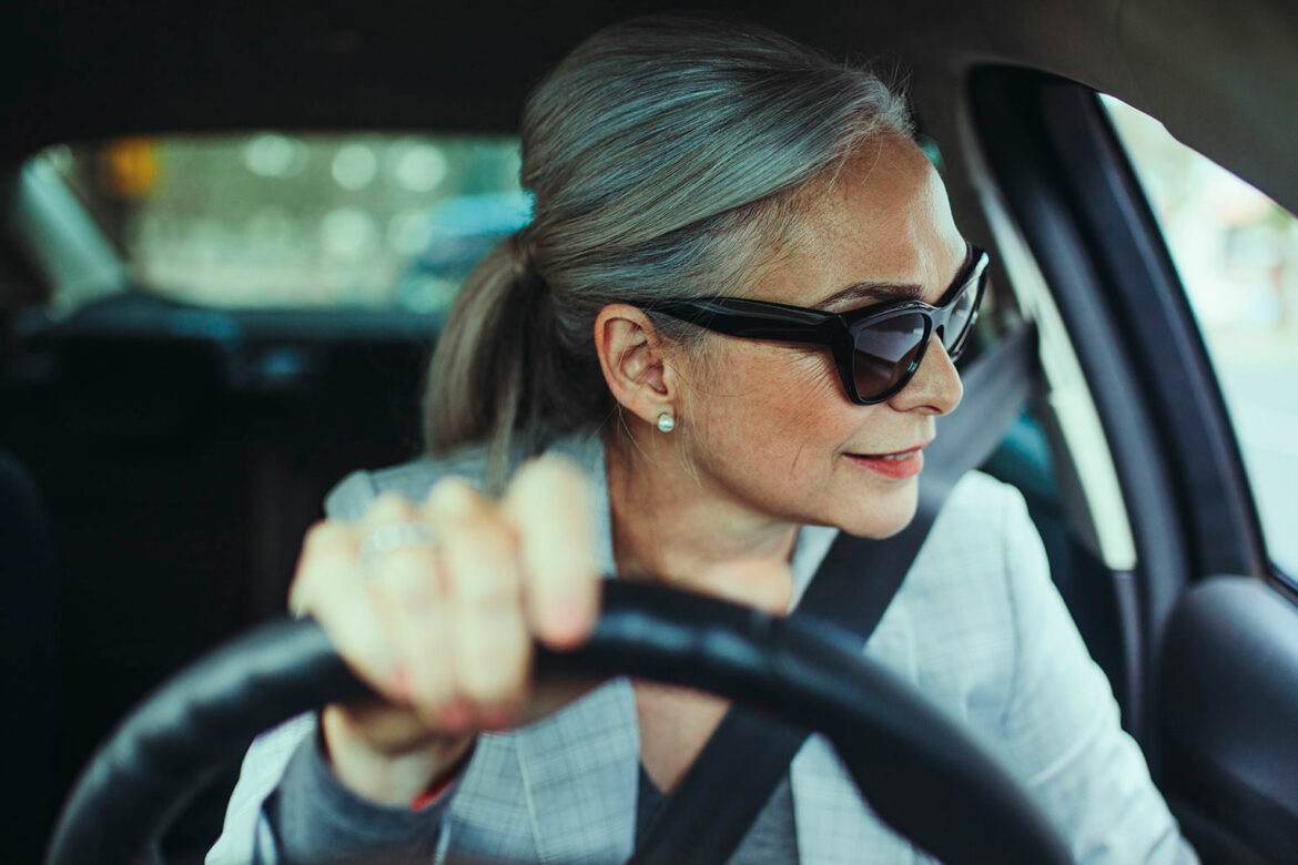 A woman in sunglasses driving a car.