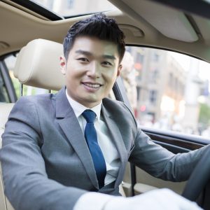 A man in a suit sitting inside of a car.
