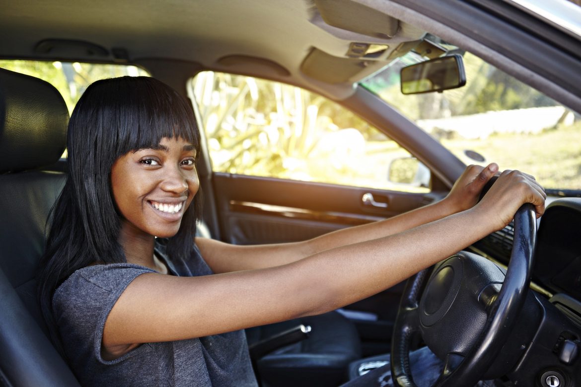 A woman sitting in her car smiling at the camera.